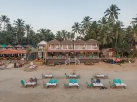 View from the beach highlighting the restaurant, sea-facing rooms, and tables in the sand to enjoy a meal.