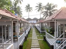 A picturesque beach resort with white walls and tiled roofs, accessible via a charming walkway