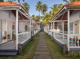 Follow the enchanting walkway to discover a beach house adorned with elegant white walls and adorned with inviting blue chairs, creating a serene oasis where relaxation and seaside bliss intertwine.